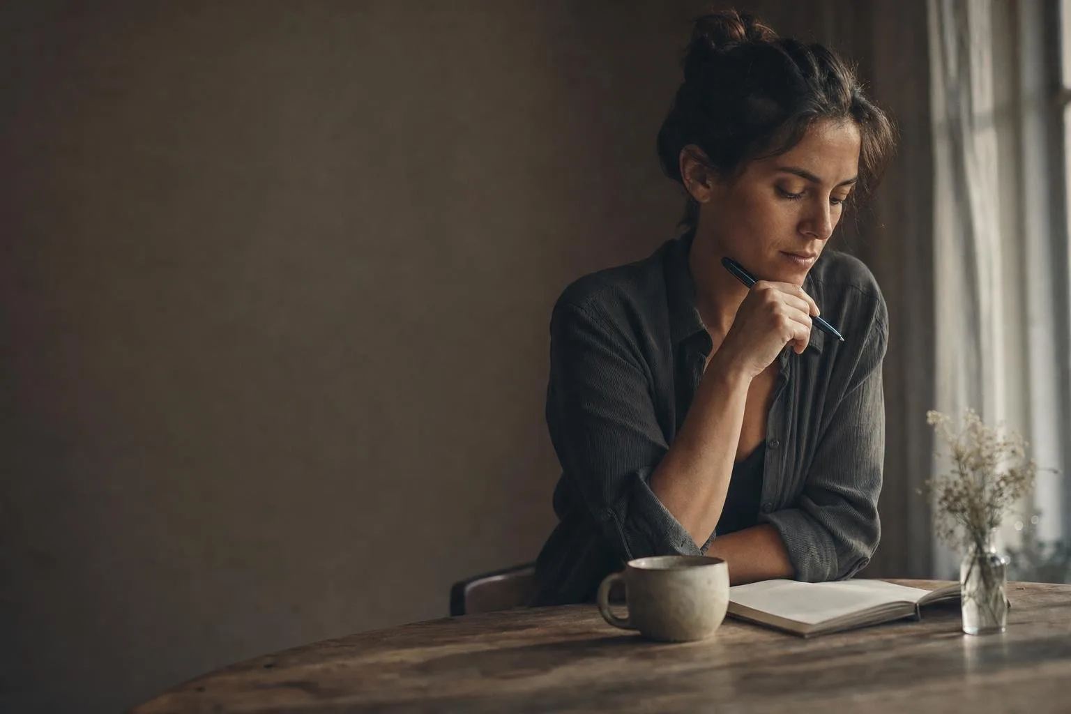 An open notebook and a cup of coffee on a warm wooden desk in morning light